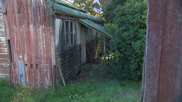 Derelict wooden house, in need of paint. Very overgrown garden.
