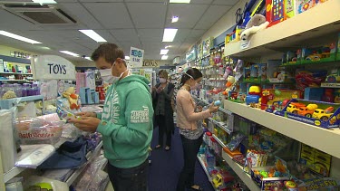 People wearing medical face mask looking at off the shelf pharmaceuticals, medicines, in pharmacy.