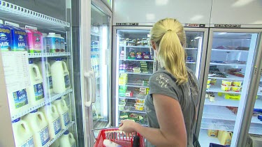 Woman in supermarket looking in dairy milk refrigerator