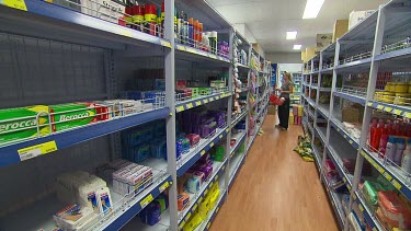 Long shot down supermarket aisles as woman shopping