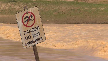 Flooding Diamantina River in middle of Simpson Desert. Sign "Danger do not swim here"
