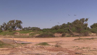 Flooding Diamantina River in middle of Simpson Desert. Circling birds above are kites feeding on the fish that are trapped by the flooding waters. The water is too turbulent for them to continue their...
