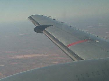 Desert below, close up of plane wing.  Lake Eyre, Simpson Desert flooded, patches of green