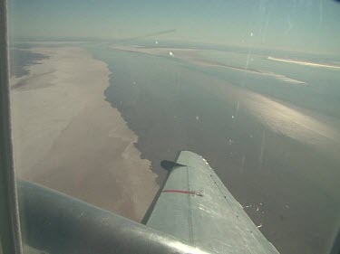 Desert below, close up of plane wing.  Lake Eyre, flooded