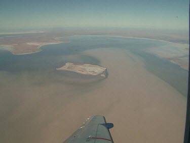 Desert below, close up of plane wing.  Lake Eyre, flooded