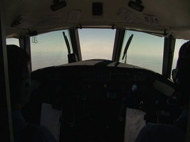 Over shoulder shot of pilots in cockpit of small plane