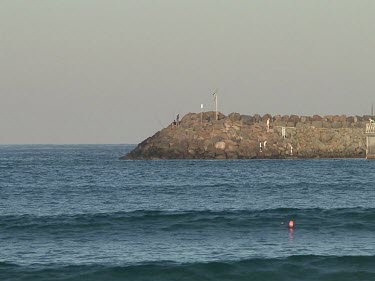 Fishermen on rocks, like a seawall.