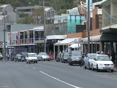 Shops on Road with Cars Driving Past.