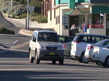 Shops on Road with Cars Driving Past.