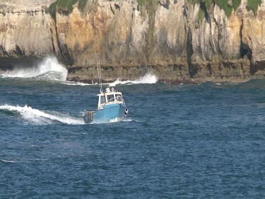 Speedboat and limestone cliffs. Small fishing boat.