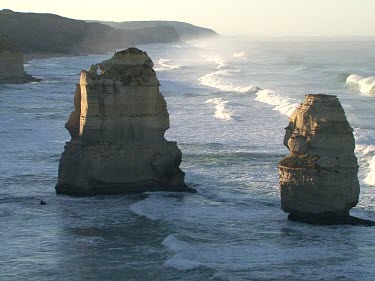Twelve Apostles, rock stacks. Limestone eroded by wave action. Sun shining and glistening on water.