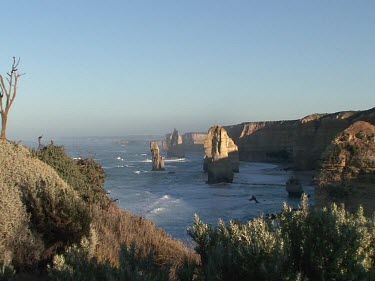 Twelve Apostles, rock stacks. Limestone eroded by wave action. Sun shining and glistening on water. Zoom in.
