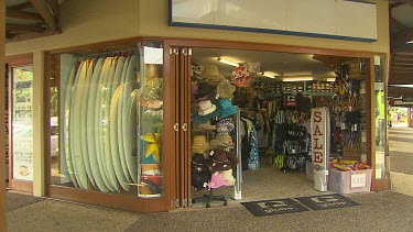 Shop with surfboards, sunhats, sale sign.