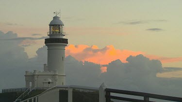 Byron Bay lighthouse. Working lighthouse with rotating lamp light. Clouds orange sunset in background.