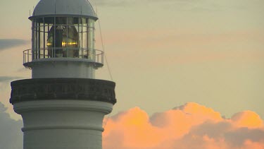 Byron Bay lighthouse. Working lighthouse with rotating lamp light. Clouds orange sunset in background.