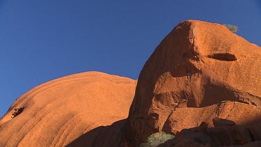 Rounded rocks Uluru. Red against blue sky.