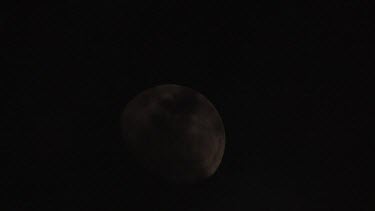 Full moon setting in dark night sky