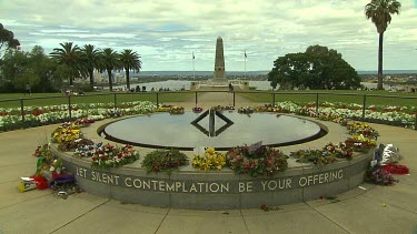 Perth Memorial to fallen soldiers of war sign Let silent contemplation be your offering floral wreaths, flowers, reflecting pool, obelisk in background. Symmetry; symmetrical;