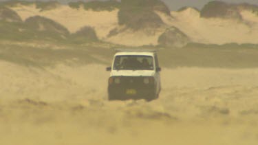 Wheels, tyre of 4wd. Four wheel drive driving on beach, approaching camera through haze of heat or sand.