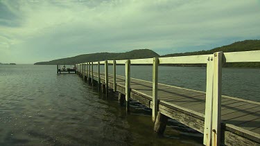 Pier on lake with two people at the end of it, recreational fishermen