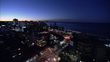 High angle wide establishing shot of Queensland Sunshine coast town Mooloolaba at night. Shows hotels and beach with palm trees, holiday atmosphere. Sunset.