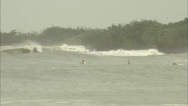 Stormy rough seas with high waves and surfers.