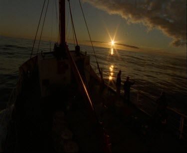 Sunset sunrise. Backlit Ship in silhouette, sun setting on horizon. Ship at sunset.
