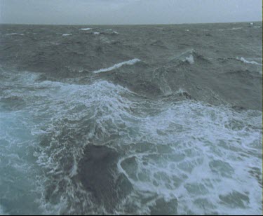 POV point of view from back of ship of ship's wake as it ploughs through the water. Waves and white surf. Big waves churning.