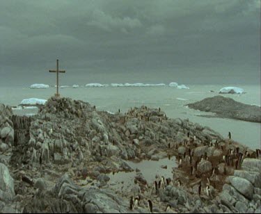 Memorial Cross to Ninnis and Mertz of Mawson expedition. Mackellar Islets with Adelie peguins.