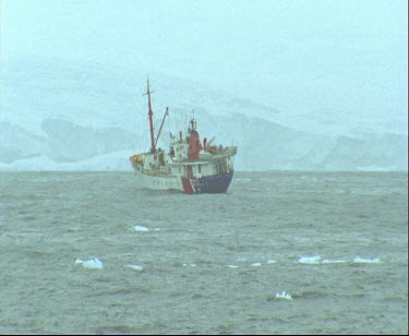 Ship in bay Antarctica, ice sheet in background.