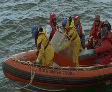 Men aboard zodiac inflatable dinghy  they are dressed for protection against the extreme cold, keeping warm .