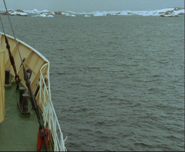 Men  aboard zodiac inflatable dinghy  setting off for land. Ice sheet ice shelf in background.