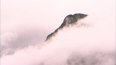 Peak of a mountain showing through thick clouds