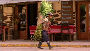 A farmer walking through Ollantaytambo with grain on his back