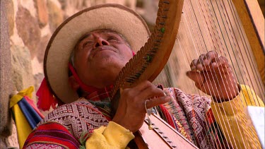 Man in traditional peruvian dress playing the harp