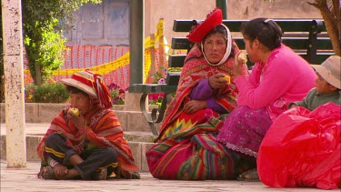 Local in traditional dress, sitting in the town square eating fruit and talking