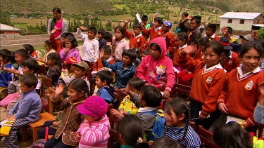 A group of school kids gathered outside, waving