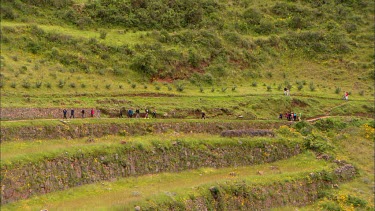 Tourist walking across rock terraces in Peru