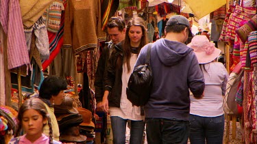 Tourists walking down a cobbled alley full of market stalls in Peru