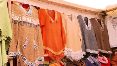 Traditional Peruvian clothes on hangers at a market stall