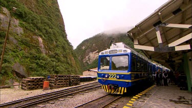 A Vista Dome train station with tourists getting off and misty mouhtains in the background