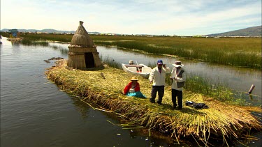 Locals of Lake Titicaca, on their hand made reed island with a hut and a speedboat tied to the island