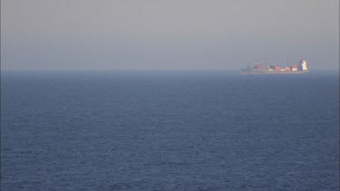 Large cargo ship in the distance on the South Pacific near New Caledoinia, going from right to left.