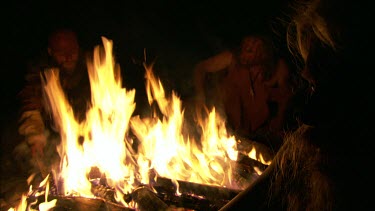 Three People sitting around a campfire