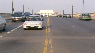 Traffic on Arlington Memorial Bridge filmed from the middle of the road with the Lincoln Memorial in the background in Washington DC
