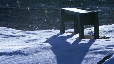 A wooden bench in a snowy rural landscape in Sweden
