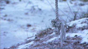 The end of a rope swing with snow in the background
