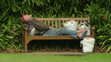 Homeless man sleeping on a bench in Sidney, Australia.