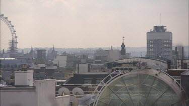 Rooftops of London. London Eye Ferris wheel on left pan to right. Big ben and Westminster in distance.