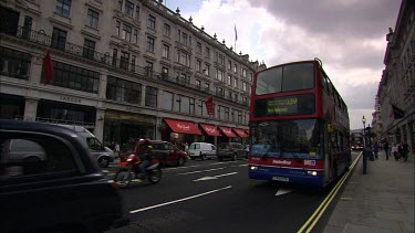 Hamley's Toy Store, Regent's Street London. Red London Double-decker bus drives past. Black taxi cab. London Street Scene.